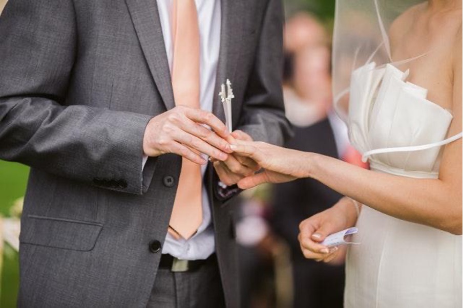 Brudgummen placerar ringen på sin bruds ringfinger