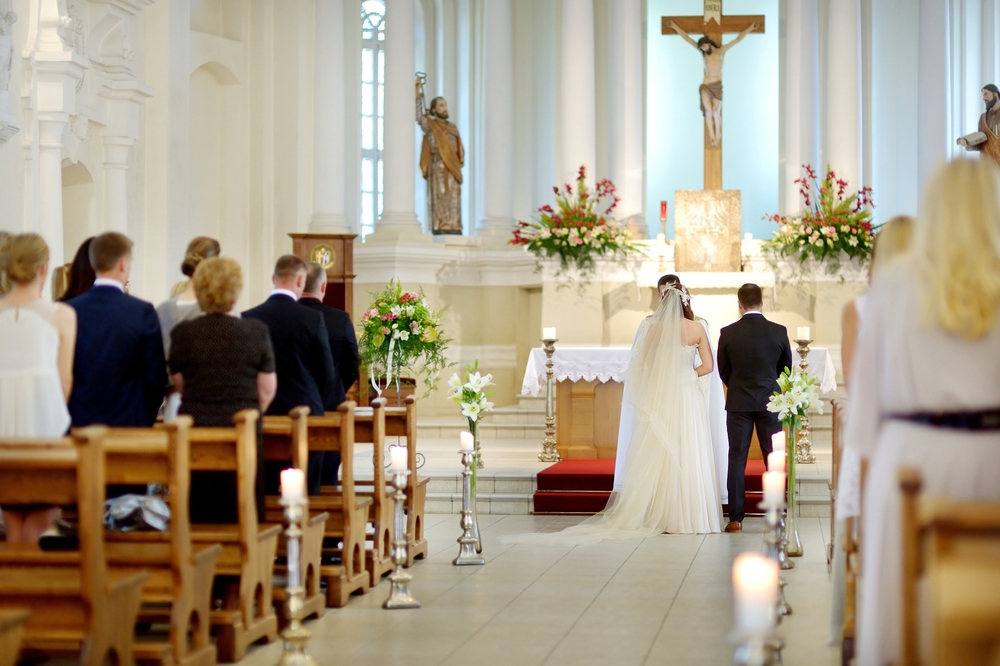 Ett brudpar står vid altaret i en kyrka framför sina gäster