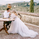 Ett brudpar sitter på en terrass med utsikt över vingårdar i Toscana