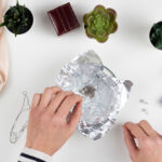 En kvinna rengör silversmycken med aluminiumfolie i botten på en skål.