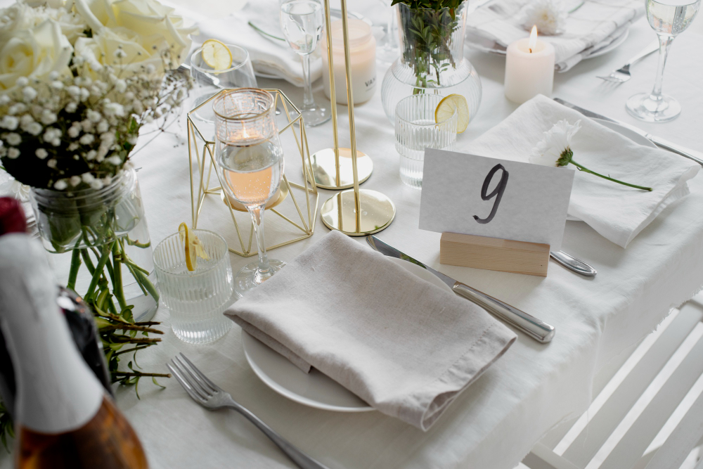Dukning med vita servetter, gulddetaljer och vita blommor