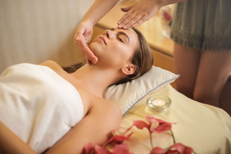 Kvinna på spa under ansiktsbehandling med ljus och blommor
